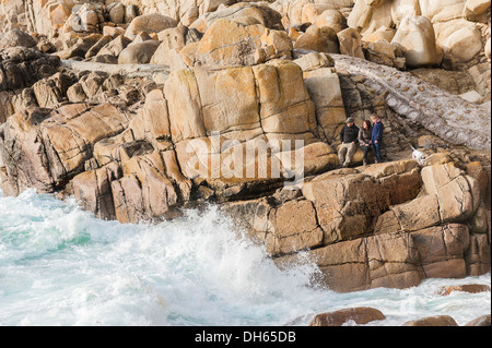 Une famille et leur chien debout sur des pierres à Porth Nanven à Cornwall. Banque D'Images