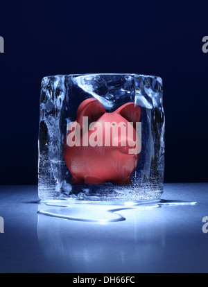 Un argent rose tirelire congelé dans un bloc de glace claire Banque D'Images
