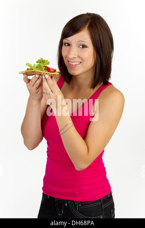 Jeune femme avec grain pain garni avec du fromage et de la tomate Banque D'Images