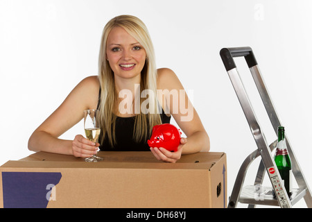 Jeune femme avec une tirelire et une boîte de déménagement Banque D'Images