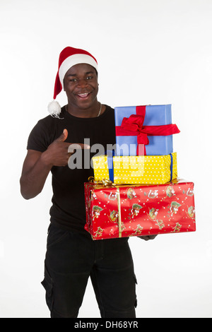 Jeune homme noir wearing a Santa hat and holding presents Banque D'Images