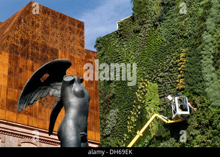 Caixa Forum, par les architectes Herzog & de Meuron, avec la sculpture du sculpteur Igor Mitoraj et travailleur dans le jardin vertical par Banque D'Images