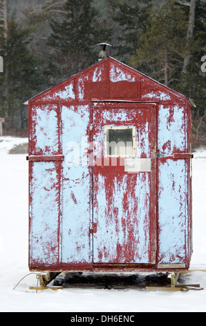 Un rouge et bleu cabane à pêche sur glace dans une tempête de neige. Banque D'Images