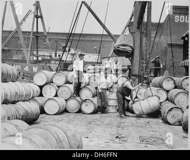 Débardeurs sur un quai de New York chargement de barils de Dyrup de maïs sur une barge sur le fleuve Hudson, ca. 1912 518287 Banque D'Images