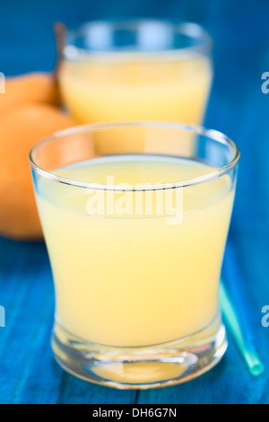 Jus de poire en verre avec des pailles sur le côté et dans le dos de poire Bosc sur bois bleu Banque D'Images