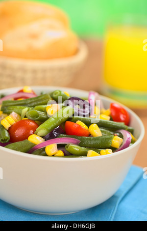 Couleur fraîche salade végétarien fait de haricots verts, tomates cerises, maïs doux, olives noires et oignons rouges dans un bol Banque D'Images