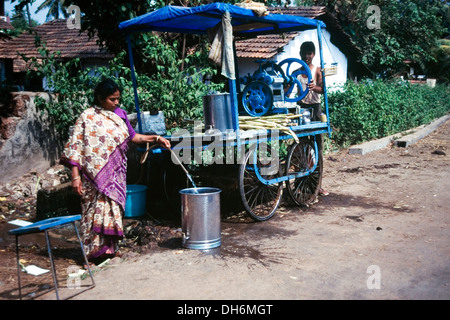 L'homme et la femme locale utiliser une presse pour faire des jus de canne à sucre à leur décrochage routière goa inde Banque D'Images