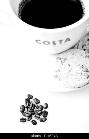Tasse de café Costa avec choc chip cookies et les grains de café sur la table Banque D'Images