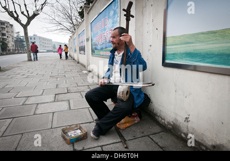 Musicien ambulant jouant sur l'un des instruments de la famille des huqin sur rue à Shanghai, Chine Banque D'Images