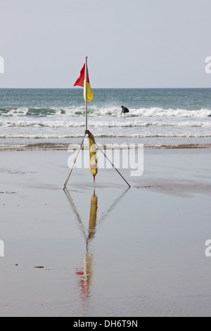 Manèges d'un surfer une vague sur la côte de Cornouailles UK off une plage surveillée par des sauveteurs de la Royal Institution Sauveteur National Banque D'Images