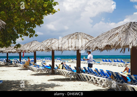 Le chaume de parasols, chaises longues et les touristes, l'île Palomino, El Conquistador Resort, Fajardo, Porto Rico Banque D'Images