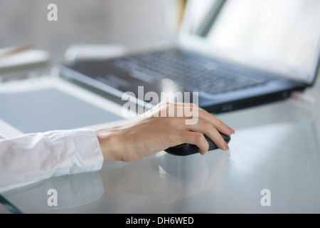 La main de femme à l'aide de la souris sans fil sur une table en verre Banque D'Images