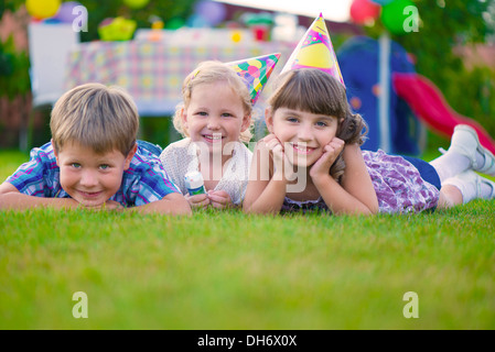 Trois petits enfants celebrating birthday on Green grass Banque D'Images