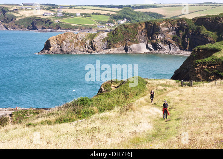 Couple en train de marcher le long du sentier côtier avec la mer bleue et les falaises en arrière-plan. Banque D'Images