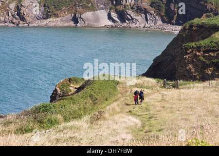 Couple en train de marcher le long du sentier côtier avec la mer bleue et les falaises en arrière-plan. Banque D'Images