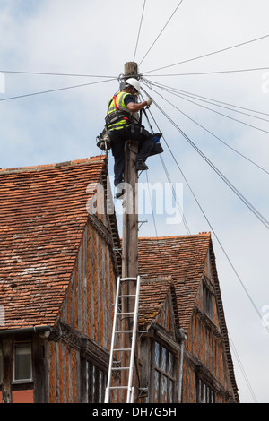 Téléphone Ingénieur travaillant sur les fils en haut d'un poteau télégraphique à l'extérieur d'un à Lavenham, Suffolk, Angleterre, Royaume-Uni, Angleterre Banque D'Images