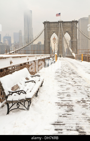 Photo verticale d'un banc recouvert de neige sur un pont de Brooklyn, presque vide après une tempête à New York City, New York Banque D'Images