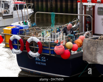 Un pêcheur de crabe rangement du matériel de pêche dans son bateau dans le port de Whitby. Le bateau "K2" un visiteur inhabituel à Exeter Whitby Banque D'Images