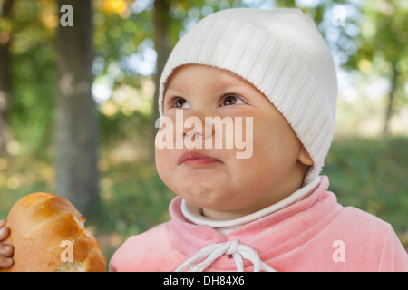 Little baby girl in autumn park mange petite tarte Banque D'Images