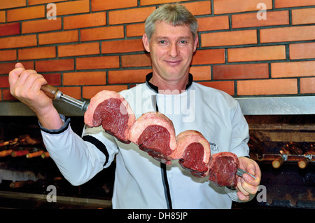 Brésil, Bento Goncalves : Grill chef avec d'énormes prêts à cracher de la viande à mettre dans le grill du restaurant Churrascaria Ipiranga Banque D'Images