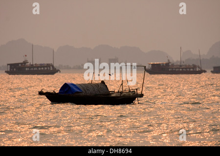 En bois traditionnelles vietnamiennes, les bateaux naviguent dans la baie de Halong au coucher du soleil, le Vietnam. Banque D'Images