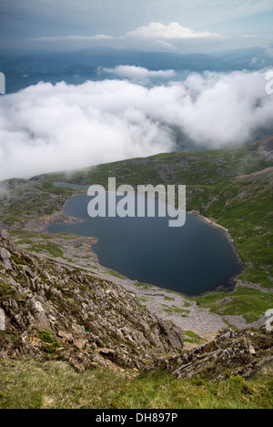 À la recherche du haut de la montagne Cadair Idris dans le parc national de Snowdonia sur Llyn y Gader avec stormy nuageux ciel d'été. Banque D'Images