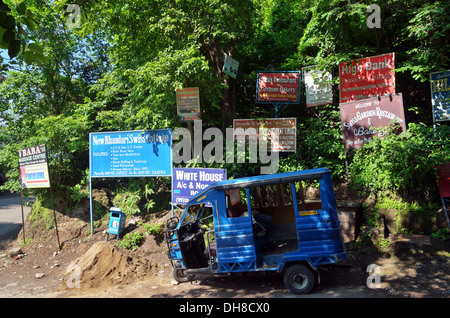 Auto rickshaw stationné contre les affiches publicitaires, dans la zone haute, Rishikesh, Inde Banque D'Images
