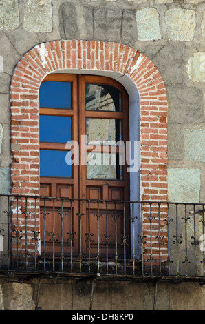 Une porte s'ouvre sur un balcon en fer forgé en édifice de briques et de pierres, Oaxaca, Mexique. Banque D'Images