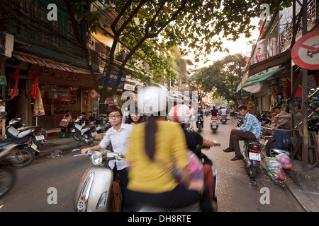 Tourné d'une rue dans le vieux quartier de Hanoi montrant les différents aspects de la vie quotidienne, y compris de nombreux scooters et vélomoteurs. Banque D'Images