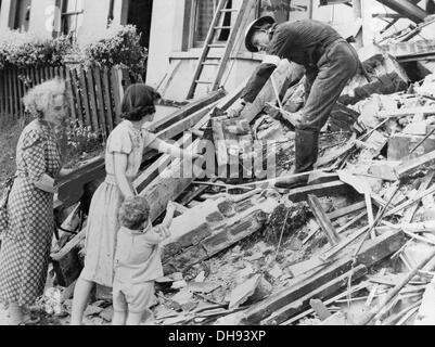 Une requête ARP mains garde une valve endommagée radio à une famille après leur accueil a été touché par des bombes allemandes pendant le Blitz. Banque D'Images