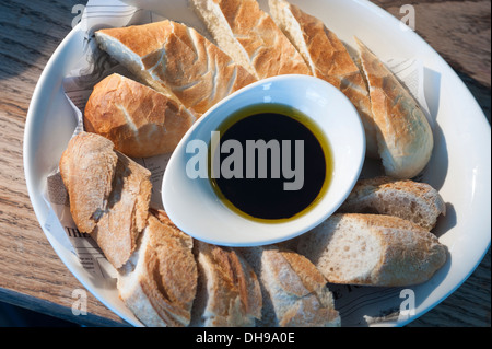 Pain servi dans un restaurant, avec une huile d'olive et le vinaigre balsamique dans le centre de la plaque. Banque D'Images