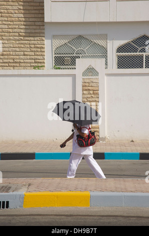 Masque de femme du Moyen Orient extrême de chaleur sous son parapluie dans la ville d'Abu Dhabi Banque D'Images