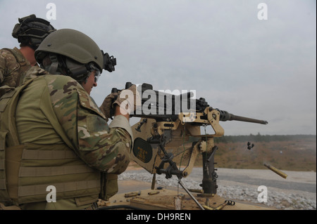 Un membre des Forces spéciales de l'armée tire un Browning M2 de calibre 50 fusil sur une cible de formation sur l'éventail d'Eglin, en Floride, le 30 octobre 2013. De vieux véhicules, les réservoirs et autres équipements lourds jonché la gamme fournissent des cibles d'entraînement physique. Banque D'Images