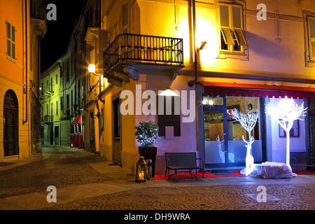 Petit restaurant sur le coin de rue avec des décorations lumineuses de Noël de cerfs et d'arbres dans la nuit dans l'Alba, l'Italie. Banque D'Images