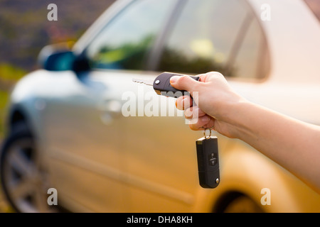 La main de la femme appuie sur la commande à distance des systèmes d'alarme de voiture Banque D'Images