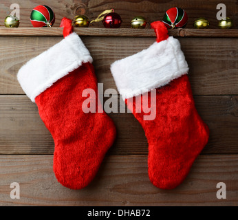 Deux bas de Noël suspendus sur une paroi en bois rustique avec sliegh cloches et des ornements. Banque D'Images