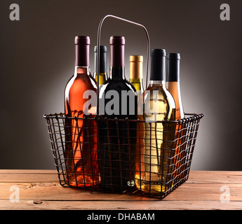 Le fil d'un panier rempli d'un assortiment de bouteilles de vin. Le panier est assis sur une table en bois rustique Banque D'Images