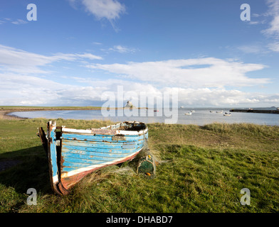 Coble en bois de bateaux de pêche sur l'Île Sainte et le lointain Château de Lindisfarne, Northumberland, England, UK Banque D'Images