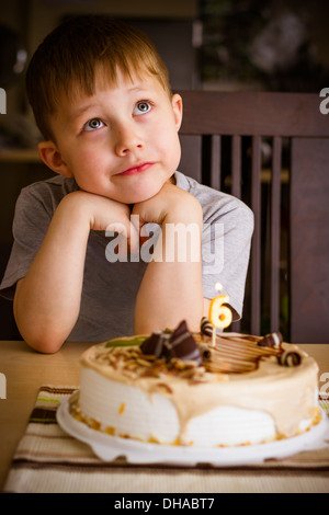 Le garçon regarde le gâteau d'anniversaire Banque D'Images