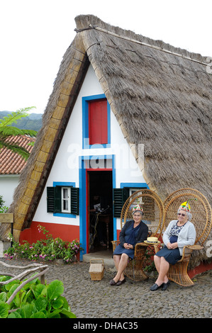 Madère au Portugal. Deux vieilles dames posent pour se faire prendre en photo devant une maison traditionnelle d'une trame de Palheiro à Santana Banque D'Images