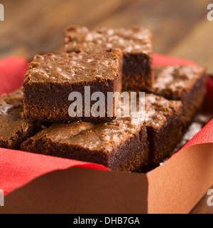 Brownies fraîchement cuits dans une boîte de papier brun avec serviette rouge (Selective Focus, Focus sur le premier brownie sur le dessus) Banque D'Images