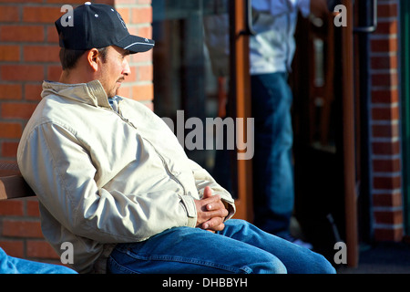 Regarder le monde, l'homme assis sur un banc. Banque D'Images