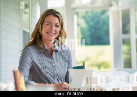 Une cuisine de la ferme. Un modèle d'une maison sur la table. La conception d'une maison. Une femme assise tenant un stylo. Banque D'Images