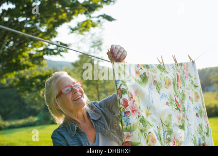 Une femme étendre le linge sur l'étendoir, dans l'air frais. Banque D'Images