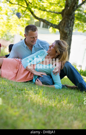 Un groupe d'adultes et d'enfants assis sur l'herbe à l'ombre d'un arbre. Une partie de la famille. Banque D'Images