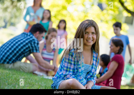 Un groupe d'adultes et d'enfants assis sur l'herbe à l'ombre d'un arbre. Une partie de la famille. Banque D'Images