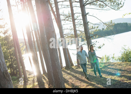 Un couple en train de marcher dans les bois sur les rives d'un lac. Banque D'Images