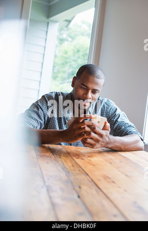 Un homme assis dans un café avec une tasse de café. Banque D'Images