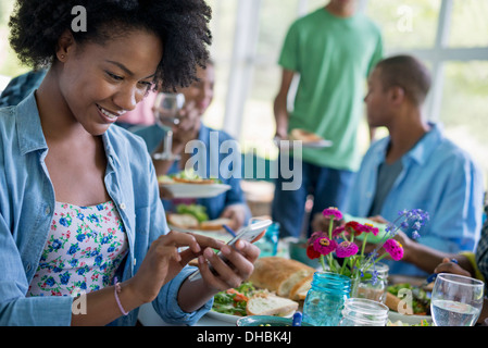 Un groupe d'hommes et de femmes autour d'une table, partager un repas dans une cuisine de la ferme. Banque D'Images