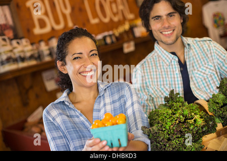 Deux personnes avec des paniers de tomates et de légumes verts à feuilles frisées. Travailler sur une ferme biologique.